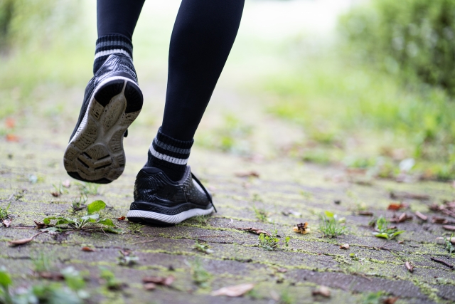 The feet of a runner walking through nature