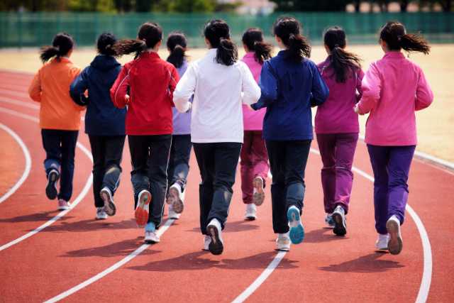 Female runners begin warming up simultaneously at the stadium.